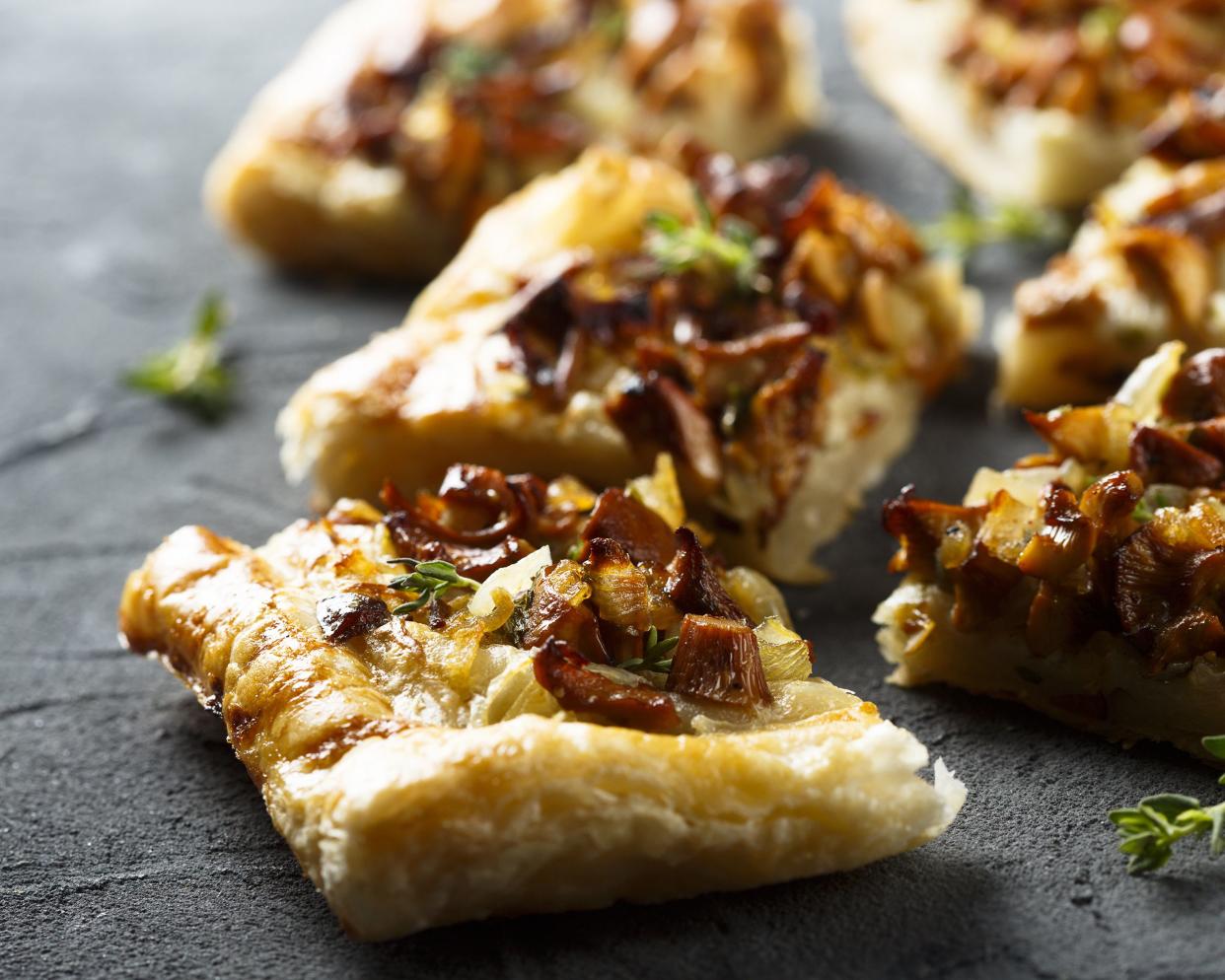 Closeup of a few onion tarts on a slab of slate with a blurred background