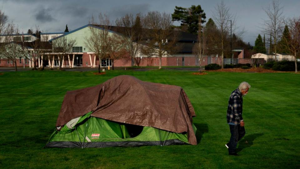 PHOTO: A homeless person walks near a tent in Fruitdale Park, Mar. 23, 2024, in Grants Pass, Ore.  (Jenny Kane/AP)