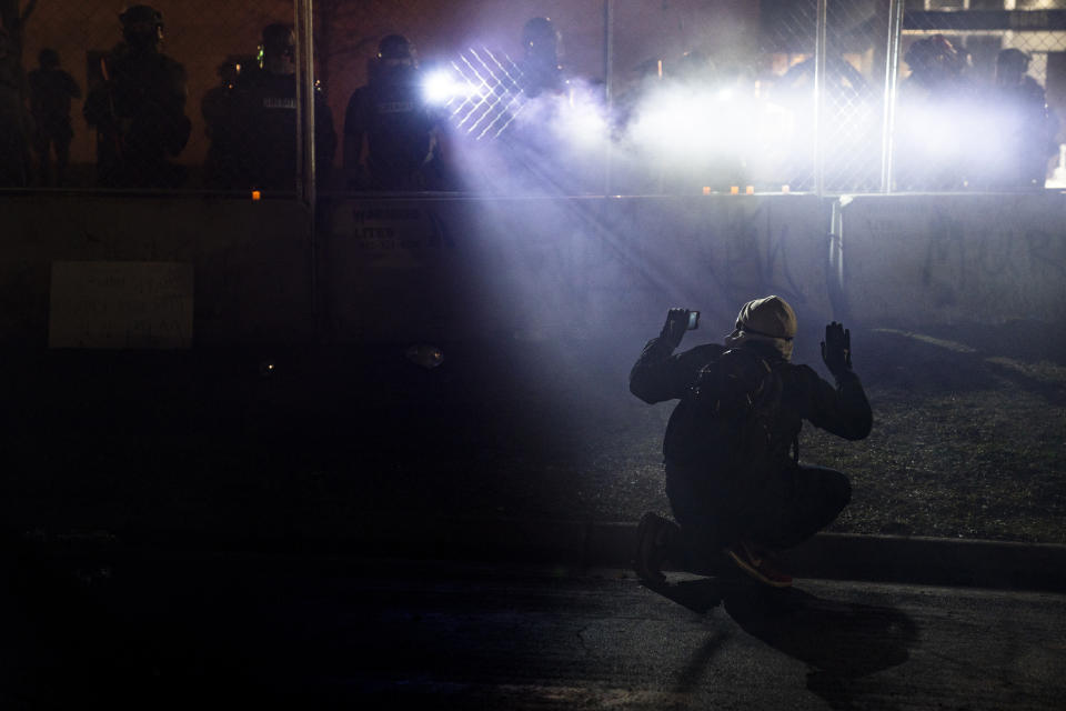 FILE- In this April 14, 2021, file photo, police shine lights on a demonstrator with raised hands during a protest outside the Brooklyn Center Police Department on in Brooklyn Center, Minn., over the fatal shooting of Daunte Wright. Brooklyn Center, the Minneapolis suburb where a white police officer fatally shot Wright, a Black motorist in April, sparking a week of protests, planned a weekend vote on a resolution calling for major changes to its policing. The resolution backed by Brooklyn Center Mayor Mike Elliott would create a new division of unarmed civilian employees to handle traffic violations and another unarmed division to respond to people in crisis. (AP Photo/John Minchillo, File)