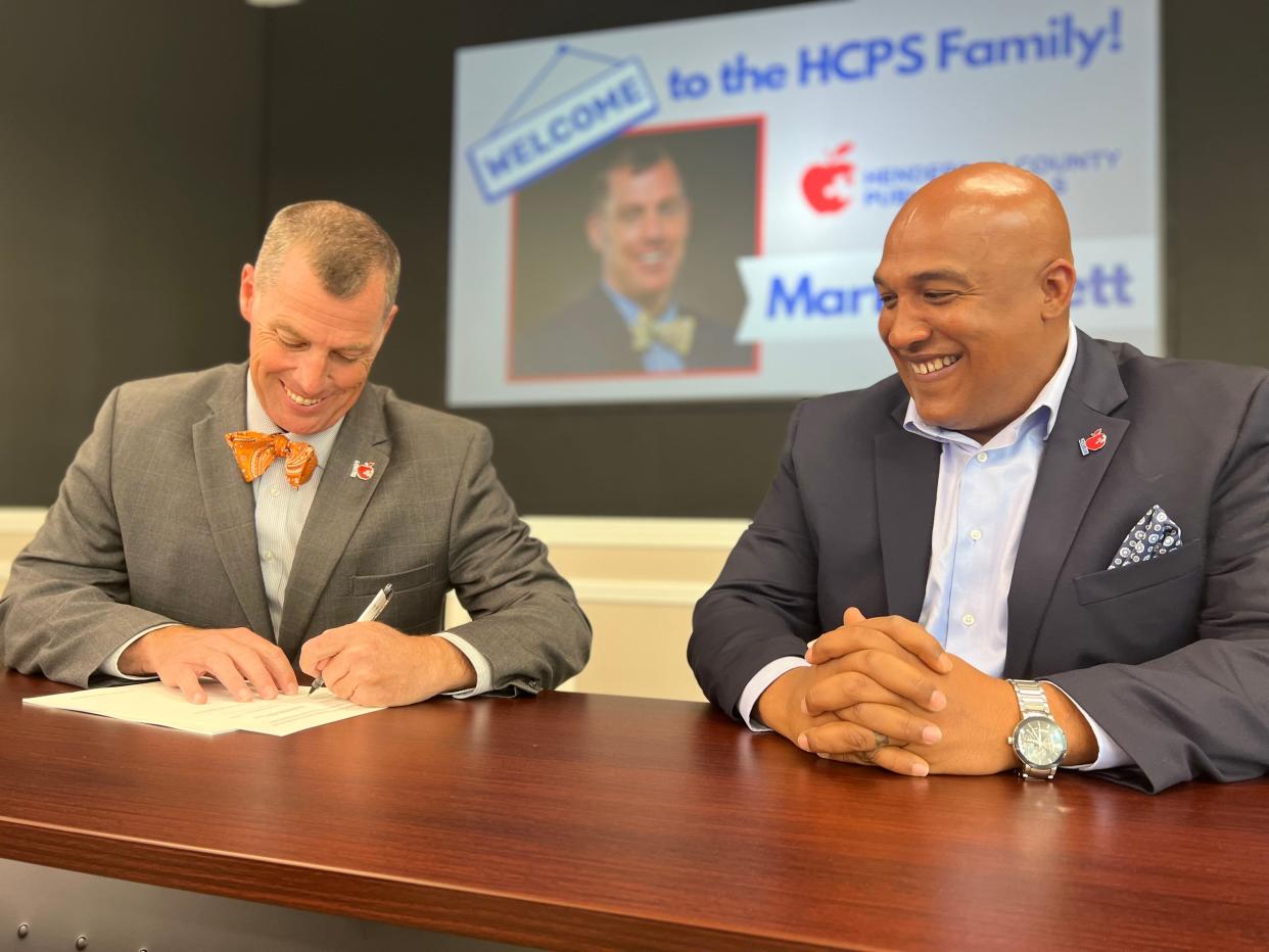 Mark Garrett (left) and Blair Craven, Chair of the Henderson County Board of Public Education (right), sign the contract of employment for the 7th superintendent of Henderson County Public Schools on Thursday. Garrett's superintendency starts July 1, 2022.