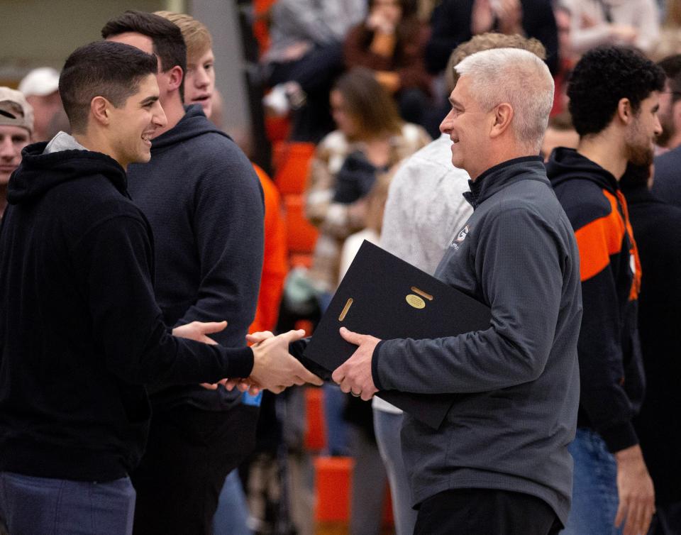 Green boys basketball coach Mark Kinsley (right) greets former players before Friday's game against Lake. Kinsley was honored for his 25th year as the Bulldogs head coach. Friday, Jan. 27, 2023.