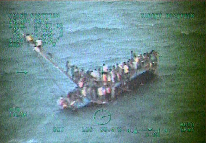 In this handout image provided by the U.S. Coast Guard, approximately 100 Haitians sit on the hull of a 40-foot sail freighter after it grounded and capsized and await rescue November 26, 2013 15 nautical miles southwest of Staniel Cay, Bahamas in the Caribbean Sea, At least 10 Haitian migrants are reported dead and approximately 100 are being rescued by U.S. Coast Guard and Royal Bahamian Defense Force rescue crews. (U.S. Coast Guard/Getty Images)