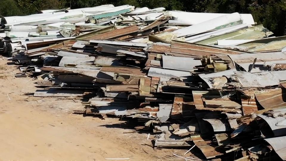 A pile of sliced wind turbine blades which resemble planks of wood.