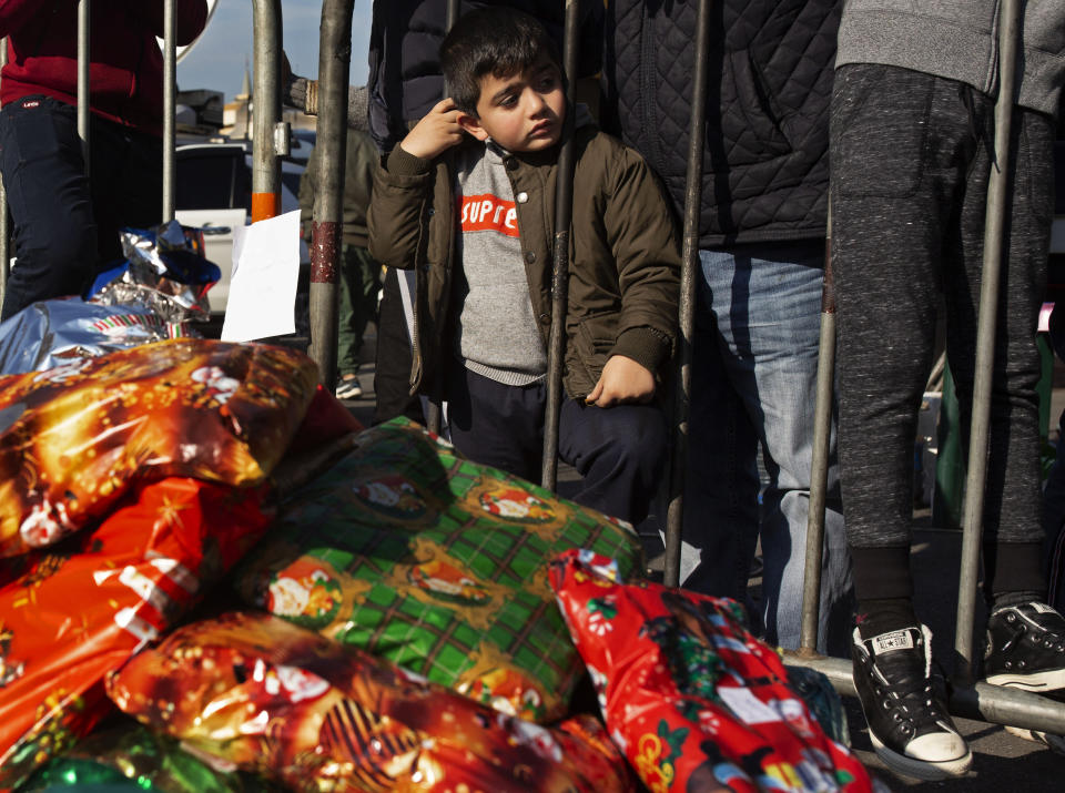 In this Sunday, Dec. 22, 2019 photo, a little boy waits for a Christmas present as anti-government protesters distribute gifts to the needy, at Martyrs' Square in Beirut, Lebanon. As Lebanon's protest movement enters its third month, the economic pinch is hurting everyone. But Lebanese are resorting to what they've done in previous wars and crises: They rely on each other, not the state. (AP Photo/Maya Alleruzzo)