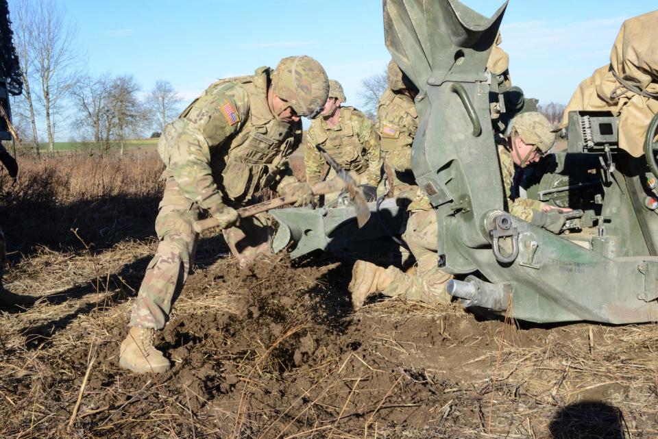 A group of Army soldiers attending to a howitzer.