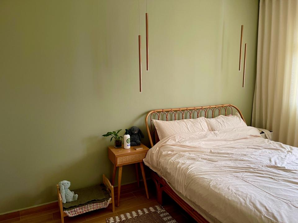 The double bed in the master bedroom next to a small wooden nightstand and a lime green coloured wall