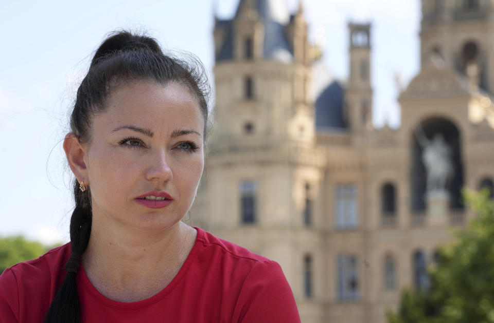 Marina Galla, a refugee from Ukraine, sits in front of the Schwerin castle during an interview with the Associated Press in Schwerin, Germany, Tuesday, Aug. 16, 2022. As Russia’s war against Ukraine reaches the sixth-month mark, many refugees are coming to the bitter realization that they will not be returning home soon. With shelling around a nuclear power plant and missiles threatening even western regions of Ukraine, many refugees don’t feel safe at home, even if those areas are under Ukrainian control. (AP Photo/Michael Sohn)