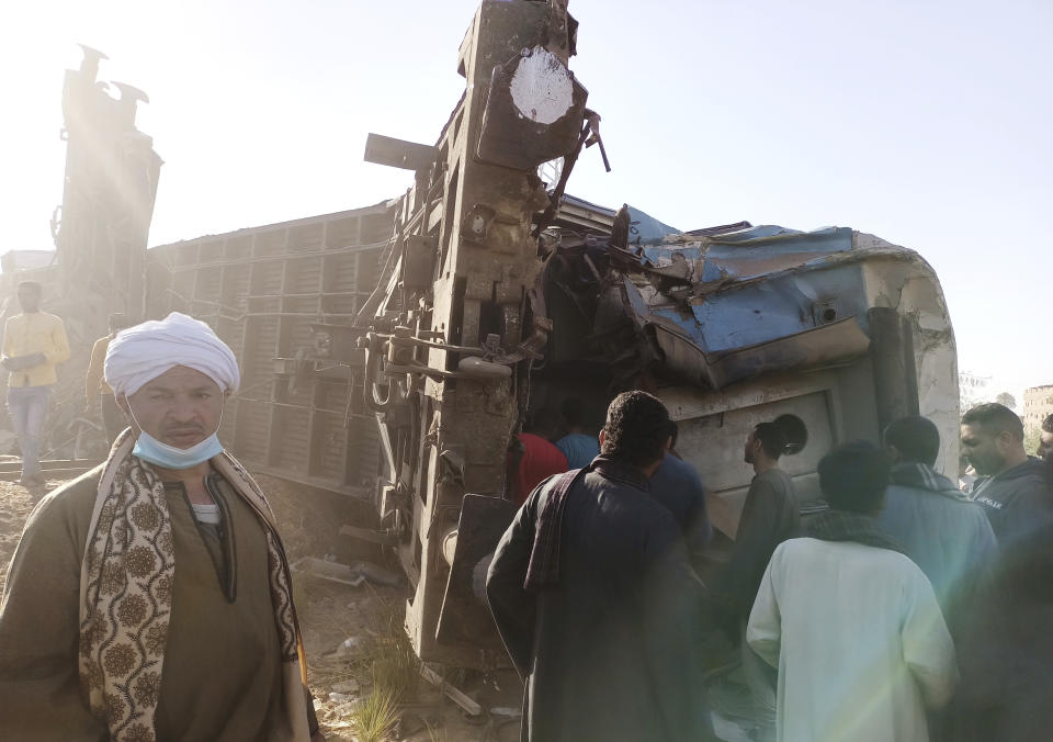 Egyptians look for remains of victims around mangled train carriages at the scene of a train accident in Sohag, Egypt, Friday, March 26, 2021. Egyptian officials say two trains collided in southern Egypt in the latest in a series of deadly accidents along Egypt's troubled rail system, which has been plagued by poor maintenance and management. (AP Photo)