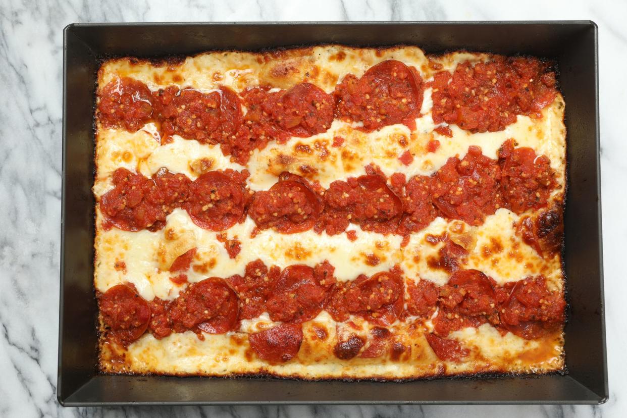 An overhead close up horizontal photograph of a freshly baked Detroit style pizza in a black baking dish