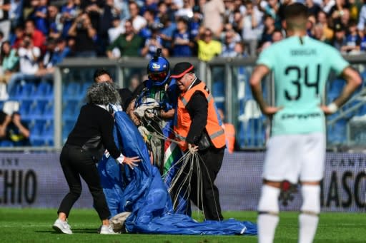 Security staff evacuate a parachutist who landed on the pitch at Sassuolo's Mapei Stadium during a game against Inter Milan