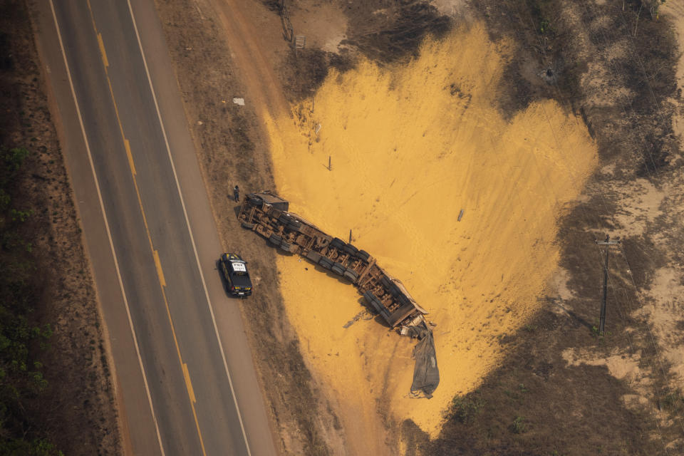 A police car sits parked next to an overturned semi-trailer truck that was hauling sand, on a highway near Porto Velho, Brazil, Friday, Aug. 23, 2019. (AP Photo/Victor R. Caivano)