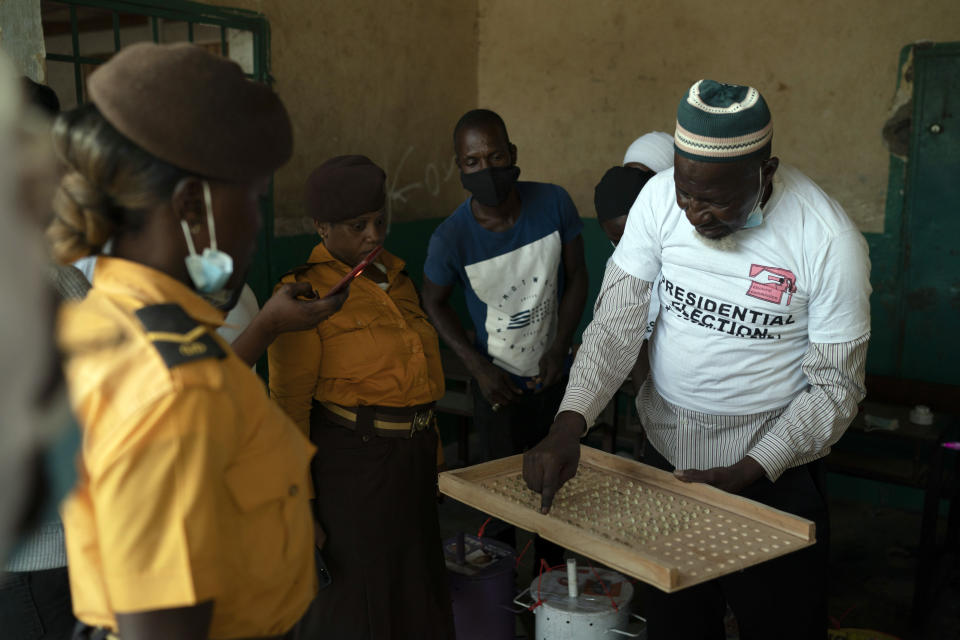 An electoral worker uses a counting board to tally marbles from a polling station during Gambia's presidential elections in Serrekunda, Gambia, Saturday, Dec. 4, 2021. Gambians vote in a historic election, one that for the first time will not have former dictator Yahya Jammeh appearing on the ballot. (AP Photo/Leo Correa)