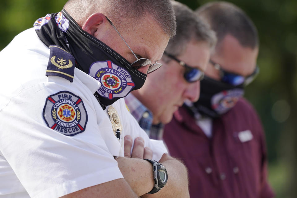 Tommy Kelley, left, of the Collierville Fire Department, prays during a vigil at the Collierville Town Hall Friday, Sept. 24, 2021, in Collierville, Tenn. The vigil is for the person killed and those injured when a gunman attacked people in a Kroger grocery store Thursday before he was found dead of an apparent self-inflicted gunshot wound. (AP Photo/Mark Humphrey)