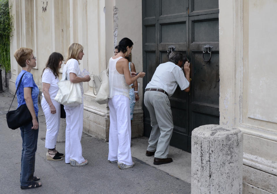 In this Sept. 7, 2013 photo, tourists look through a spy hole in the door of a villa of the Order of the Knights of Malta to get a glimpse of St. Peter's Basilica, in Rome. The villa, owned by the Knights of Malta atop the ancient Aventine Hill, has a large entry door with a celebrated keyhole. If you peer through it, you’ll have a perfectly framed view of the dome of St. Peter’s Basilica. (AP Photo/Michele Barbero)