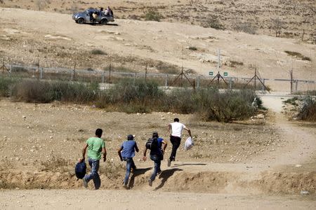 Palestinian labourers from the West Bank illegally cross Israel's controversial barrier in the southern West Bank in this June 22, 2013 file photo. REUTERS/Ammar Awad/Files