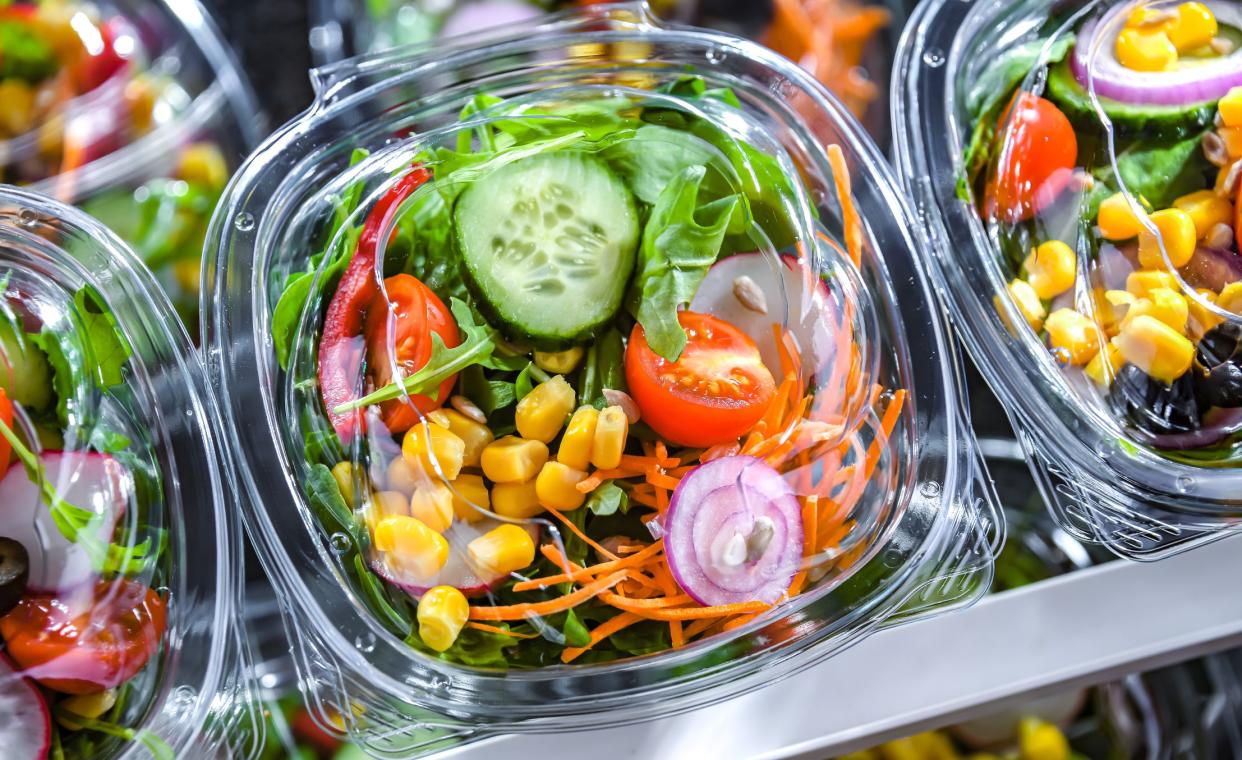 Plastic boxes with pre-packaged vegetable salads, put up for sale in a commercial refrigerator