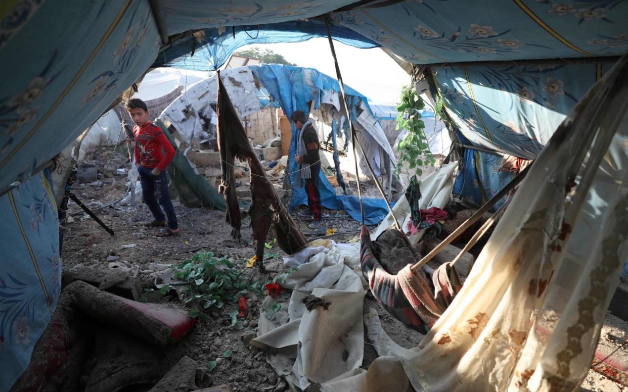 Young boys inspect the damage following Syrian regime bombardment on a makeshift camp in the village of Qah near the Turkish border in the northwestern Idlib - AFP