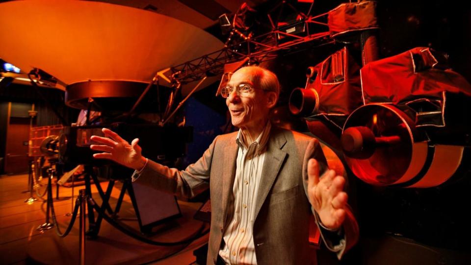 Ed Stone gestures in front of a red background