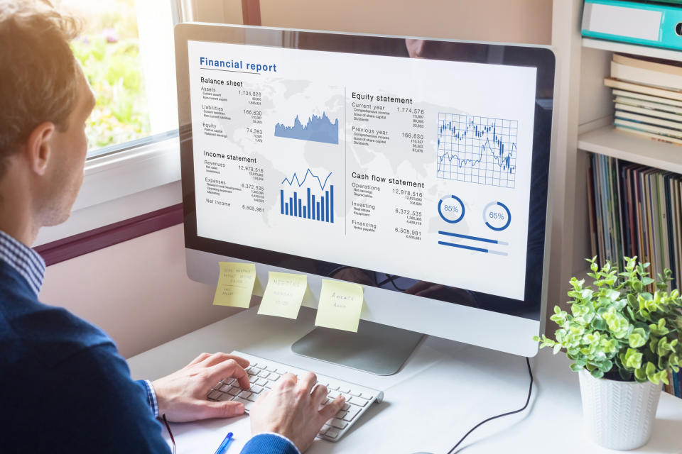 An investor works at a computer with financial charts on the screen.