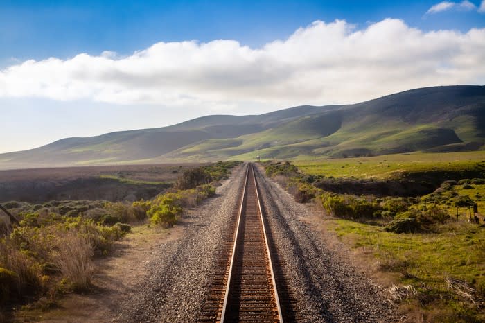 A single railroad track leading into the distance in a bucolic landscape