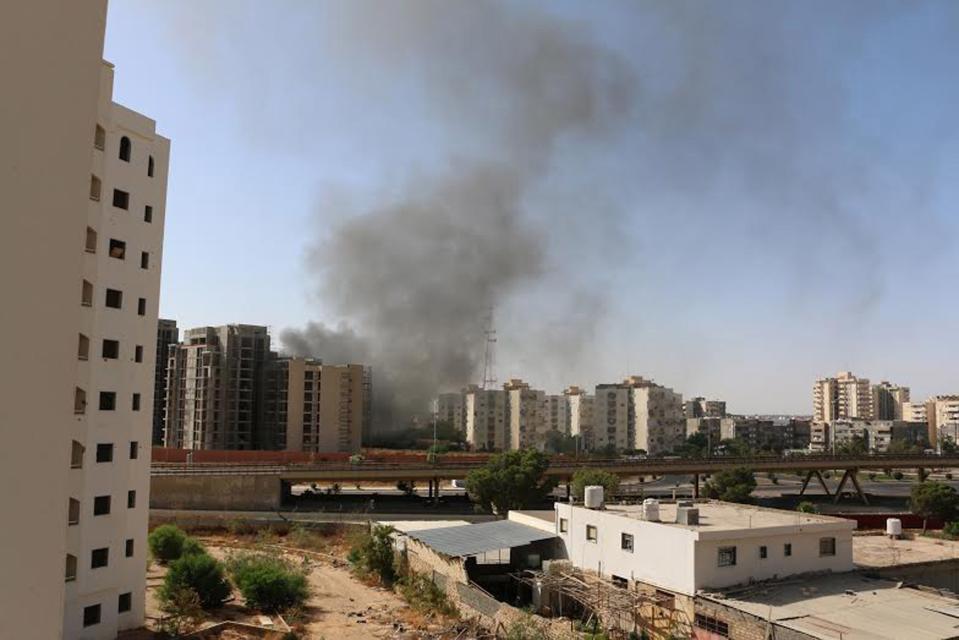 Smoke rises near buildings after heavy fighting between rival militias broke out near the airport in Tripoli July 13, 2014. Heavy fighting broke out between rival militias near the airport of the Libyan capital Tripoli on Sunday, residents and officials said, reporting explosions and gunfire that forced the suspension of all flights. REUTERS/ Hani Amara(LIBYA - Tags: POLITICS CIVIL UNREST)