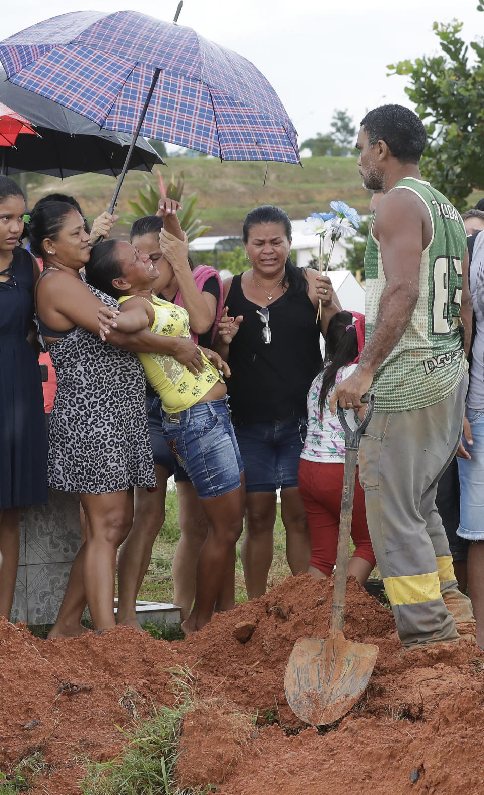 Antonia Alves, in yellow top, is comforted by relatives during the burial of her son Jairo Alves Figueiredo, an inmate who was killed in the recent prison riots, at a cemetery in Manaus, Brazil, Thursday, May 30, 2019. Families were burying victims of several prison riots in which dozens of inmates died in the northern Brazilian state of Amazonas, as authorities confirmed they had received warnings of an “imminent confrontation” days before the attacks begun. (AP Photo/Andre Penner)