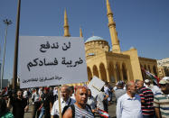 A Lebanese retired soldier holds an Arabic placard that reads: "Will not pay your corruption taxes," as he protests near the parliament building where lawmakers and ministers are discussing the draft 2019 state budget, in Beirut, Lebanon, Tuesday, July 16, 2019. The lawmakers have begun discussing the budget amid tight security and limited protests against proposed austerity measures. The proposed budget aims to avert a financial crisis by raising taxes and cutting public spending in an effort to reduce a ballooning deficit. (AP Photo/Hussein Malla)