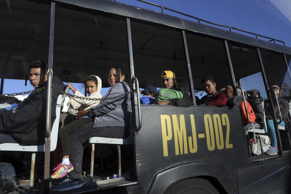 Members of a Central American migrant caravan hoping to reach the U.S. border travel in a police bus in Guadalajara, Mexico, Tuesday, Nov. 13, 2018. The thousands of Central American migrants left shelters in Guadalajara early Tuesday and were taken by bus to a highway tollbooth to wait for rides to their next destination, however, no other buses showed up and few trucks passed to pick them up, leaving many to walk. (AP Photo/Rodrigo Abd)