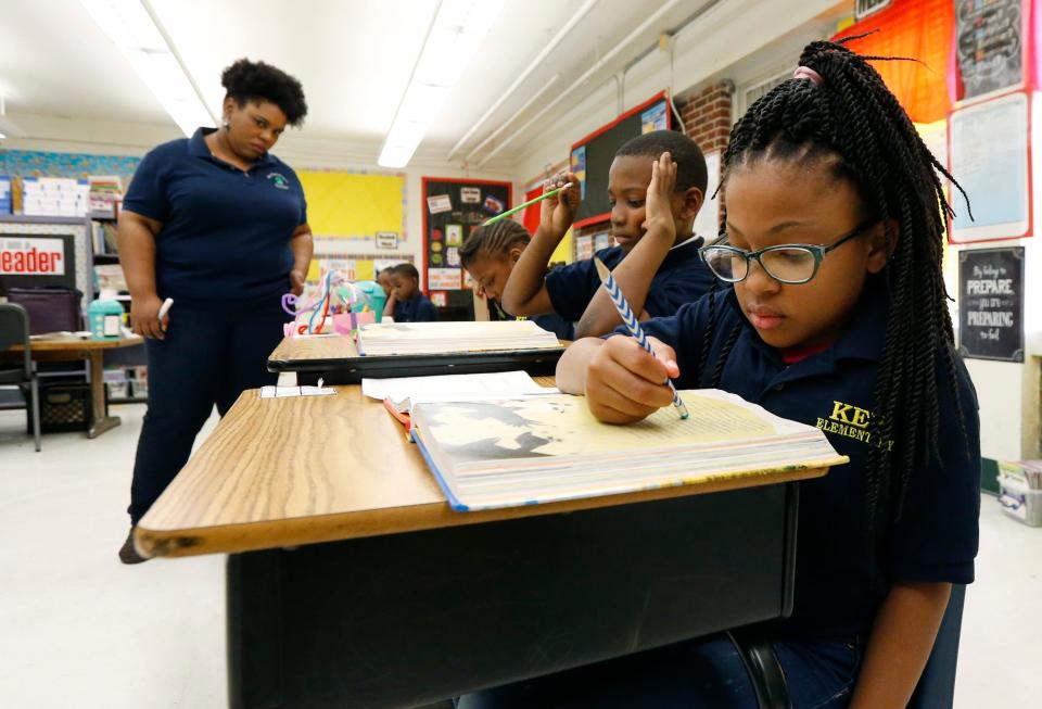 Elize'a Scott, a Jackson, Mississippi, student, right, reads under the watchful eyes of teacher Crystal McKinnis, left.