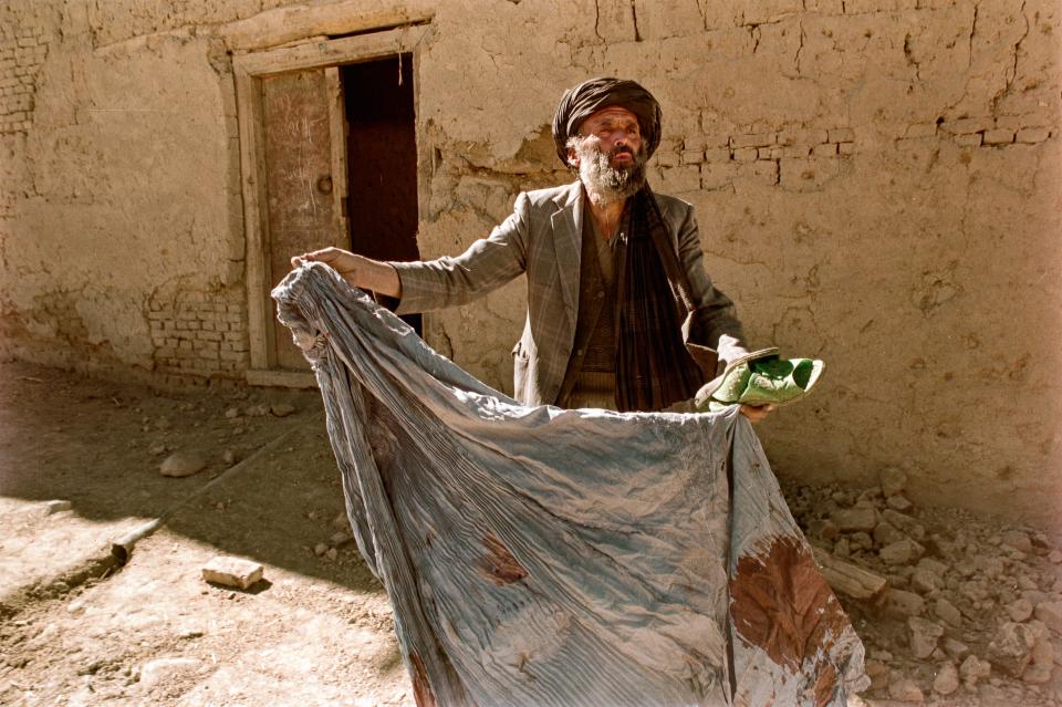 A man displays a bloodied piece of fabric.