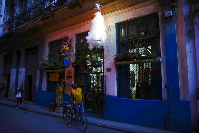 us-buArtist Generoso Betancourt looks at his Christmas tree hanging over the door of his studio in downtown Havana, Cuba