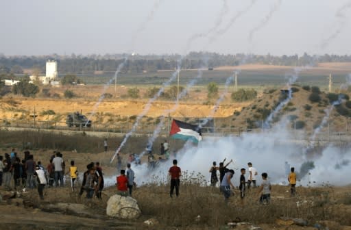 Palestinian protesters flee from tear gas fired by Israeli forces across the fence during clashes along the border in the central Gaza Strip