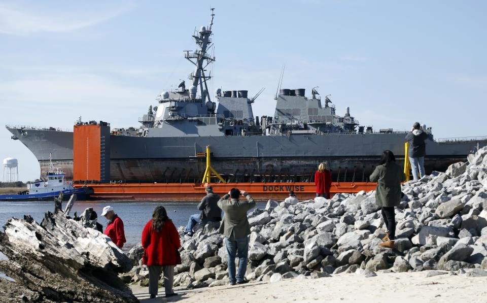 FILE - In this Jan. 19, 2018, file photo, area residents watch the transport vessel Transshelf carry the damaged USS Fitzgerald, the U.S. Navy destroyer damaged in a June 2017 collision off Japan, up the Pascagoula River in Pascagoula, Miss. Survivors and descendants of those killed when a container ship collided with the U.S. Navy destroyer off Japan's coast are suing the ship's Japanese charterer, according to a lawsuit filed Monday, Nov. 18, 2019, that details the survivors' scramble for safety as water rushed in. (AP Photo/Rogelio V. Solis, File)