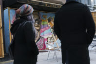 People walk past a mural of Supreme Court Justice Ruth Bader Ginsburg that was painted on a boarded up restaurant along I Street NW, Friday, Oct. 30, 2020, in downtown Washington near the White House. This restaurant has been boarded since protests this summer. (AP Photo/Jacquelyn Martin)