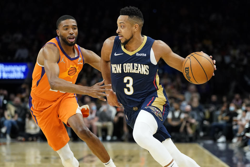 New Orleans Pelicans guard CJ McCollum (3) drives as Phoenix Suns forward Mikal Bridges defends during the first half of an NBA basketball game, Friday, Feb. 25, 2022, in Phoenix. (AP Photo/Matt York)