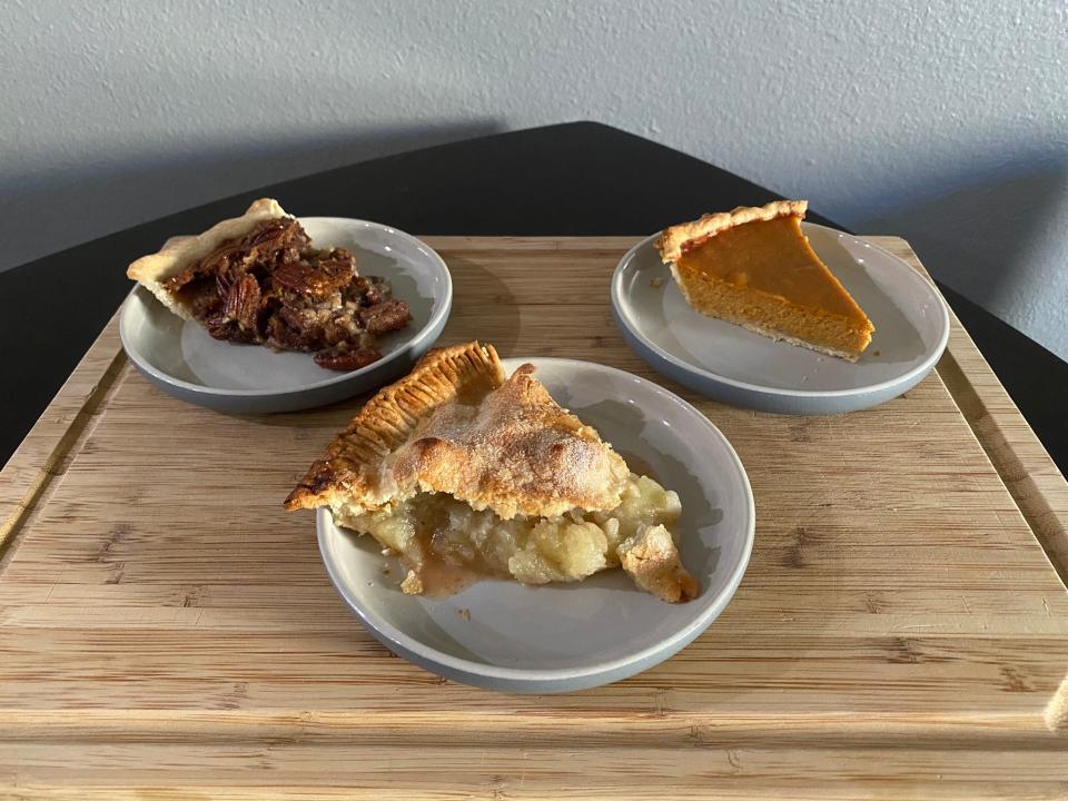 slice of pecan pie on a plate, slice of apple pie on a plate, and slice of pumpkin pie on a plate