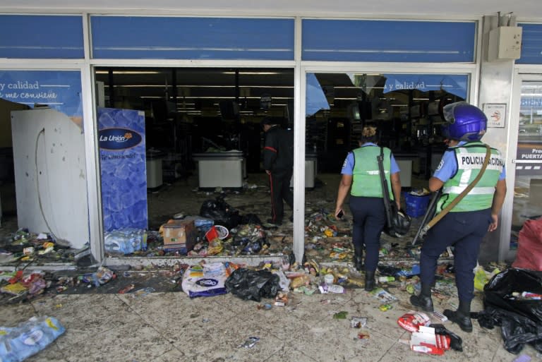 Police officers enter a supermarket after lootings during anti-government protests