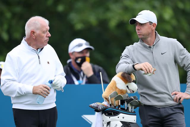 <p>Warren Little/Getty</p> Rory McIlroy and his father, Gerry, on the green ahead of the Dubai Duty Free Irish Open in Ireland in June 2021.