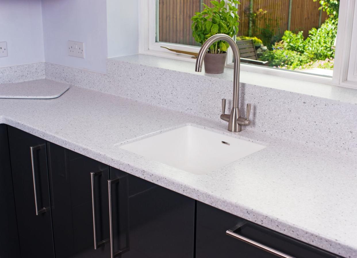 state of the art domestic kitchen with hi gloss grey cupboards and oak cabinets and induction hob, set in a stone resin worktop