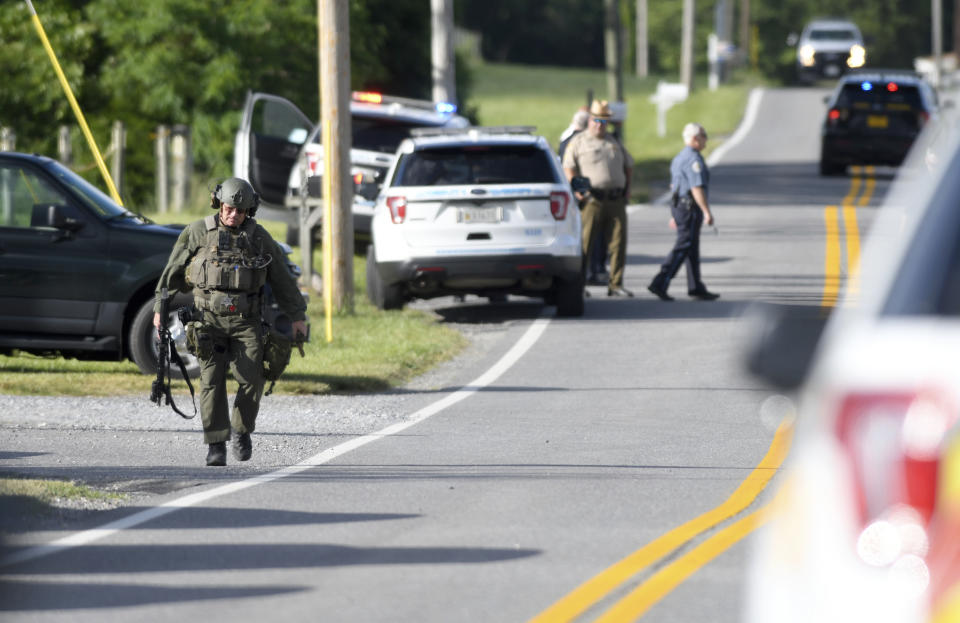 A tactical police officer walks near where a man opened fire at a business, killing three people before the suspect and a state trooper were wounded in a shootout, according to authorities, in Smithsburg, Md., Thursday, June 9, 2022. The Washington County (Md.) Sheriff's Office said in a news release that three victims were found dead at Columbia Machine Inc. and a fourth victim was critically injured. (AP Photo/Steve Ruark)