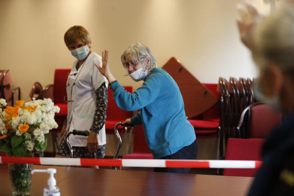 In this April 21, 2020, photo, Monique Hernent, 65, waves goodbye to her sister visiting her at the Kaysersberg nursing home, eastern France. France has started to break the seals on its locked down nursing homes, allowing limited visitation rights for the families of elderly residents. The visits are proving bittersweet for some, too short and restricted to make up for weeks of isolation and loneliness. But they are shedding light on the immense emotional toll caused by locking down care homes. (AP Photo/Jean-Francois Badias)