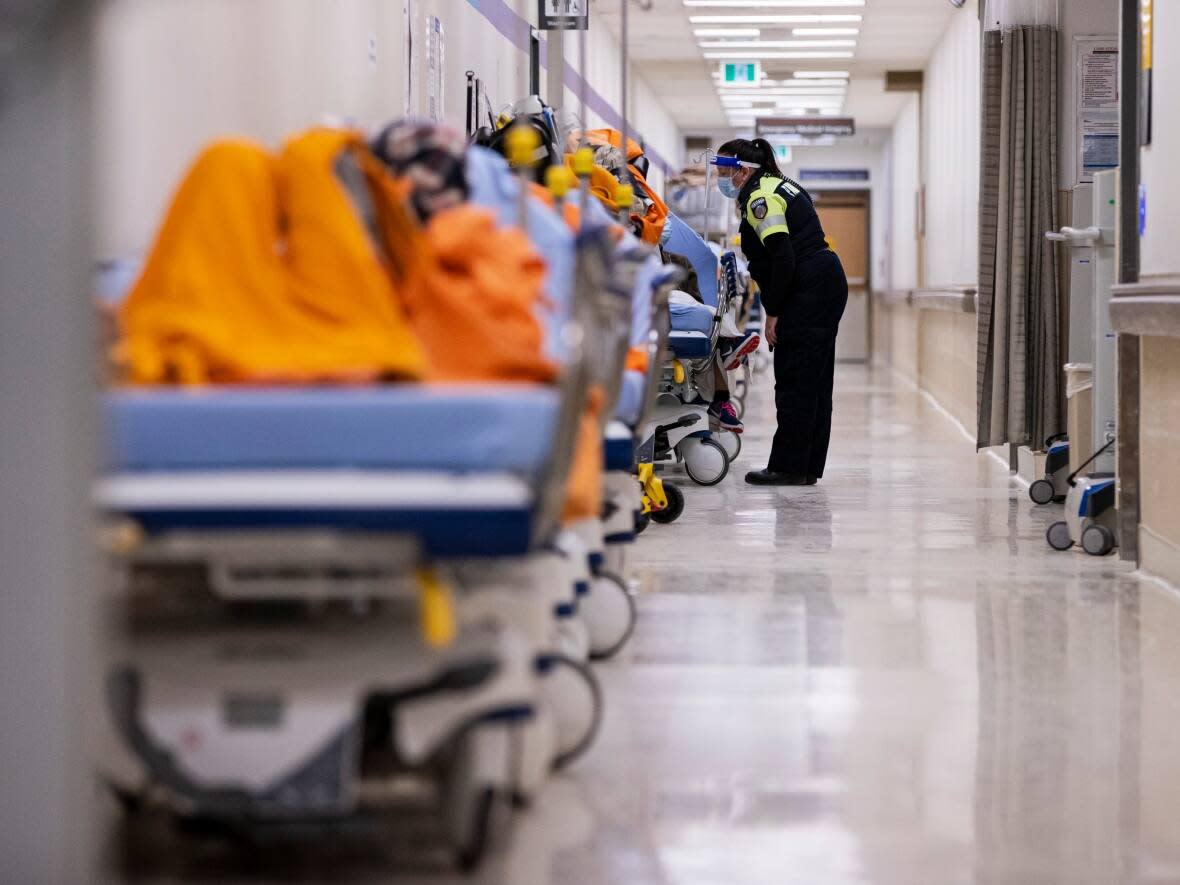 A paramedic checks in on a patient waiting in the hallway of the Humber River Hospital emergency department on Jan. 13, 2022. (Evan Mitsui/CBC - image credit)