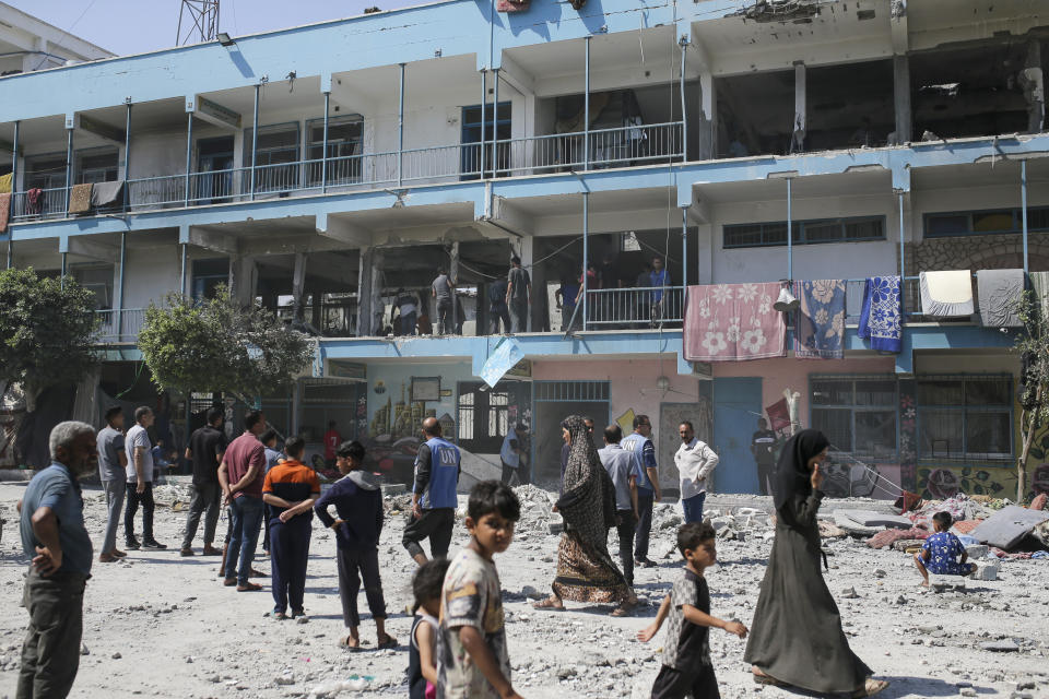 Palestinians look at the aftermath of the Israeli strike on a U.N.-run school that killed dozens of people in the Nusseirat refugee camp in the Gaza Strip, Thursday, June 6, 2024. An Israeli strike early Thursday on a school sheltering displaced Palestinians in central Gaza killed more than 30 people, including 23 women and children, according to local health officials. The Israeli military said that Hamas militants were operating from within the school. (AP Photo/Jehad Alshrafi)