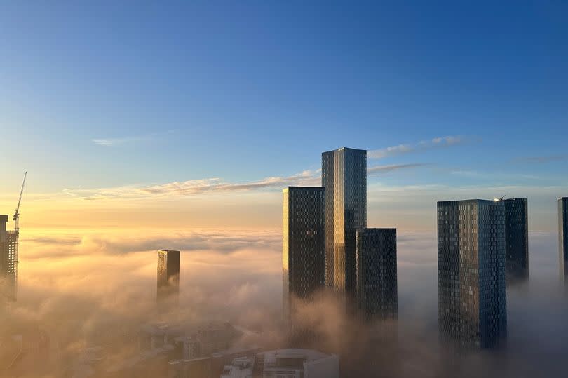 Skyscrapers in Manchester appear above clouds