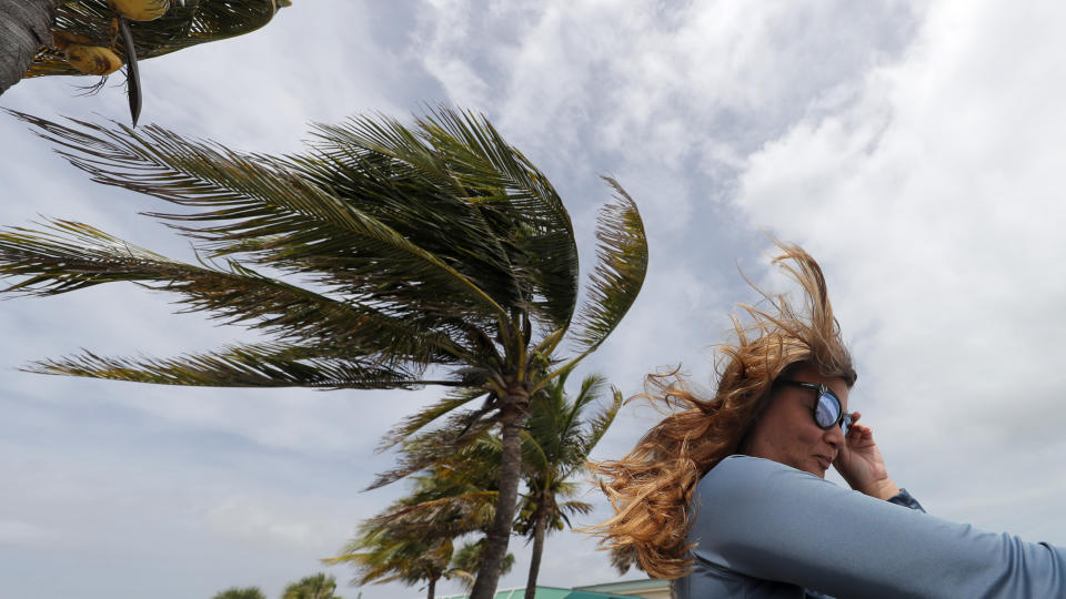 Kristen Davis watches the high surf from a boardwalk overlooking the Atlantic Ocean, as winds from Hurricane Dorian blow the fronds of a palm tree in Vero Beach, Fla., Monday, Sept. 2, 2019. (AP Photo/Gerald Herbert)