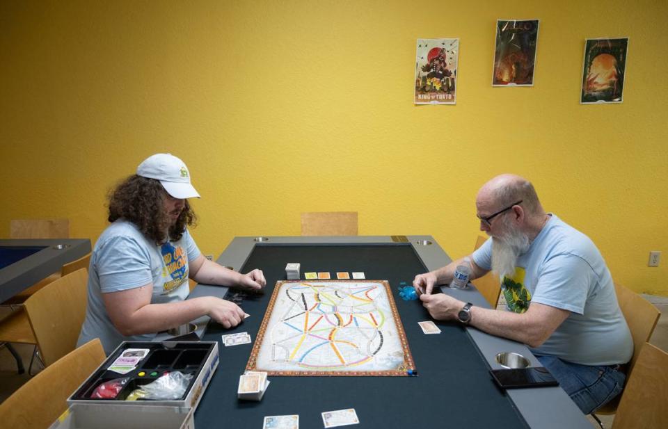 Rob Van Tuinen, left, and his father Bob Van Tuinen demonstrate the game Ticket to Ride on one of the gaming tables at Meeple Valley Board Game Cafe in Modesto, Calif., Thursday, March 21, 2024.