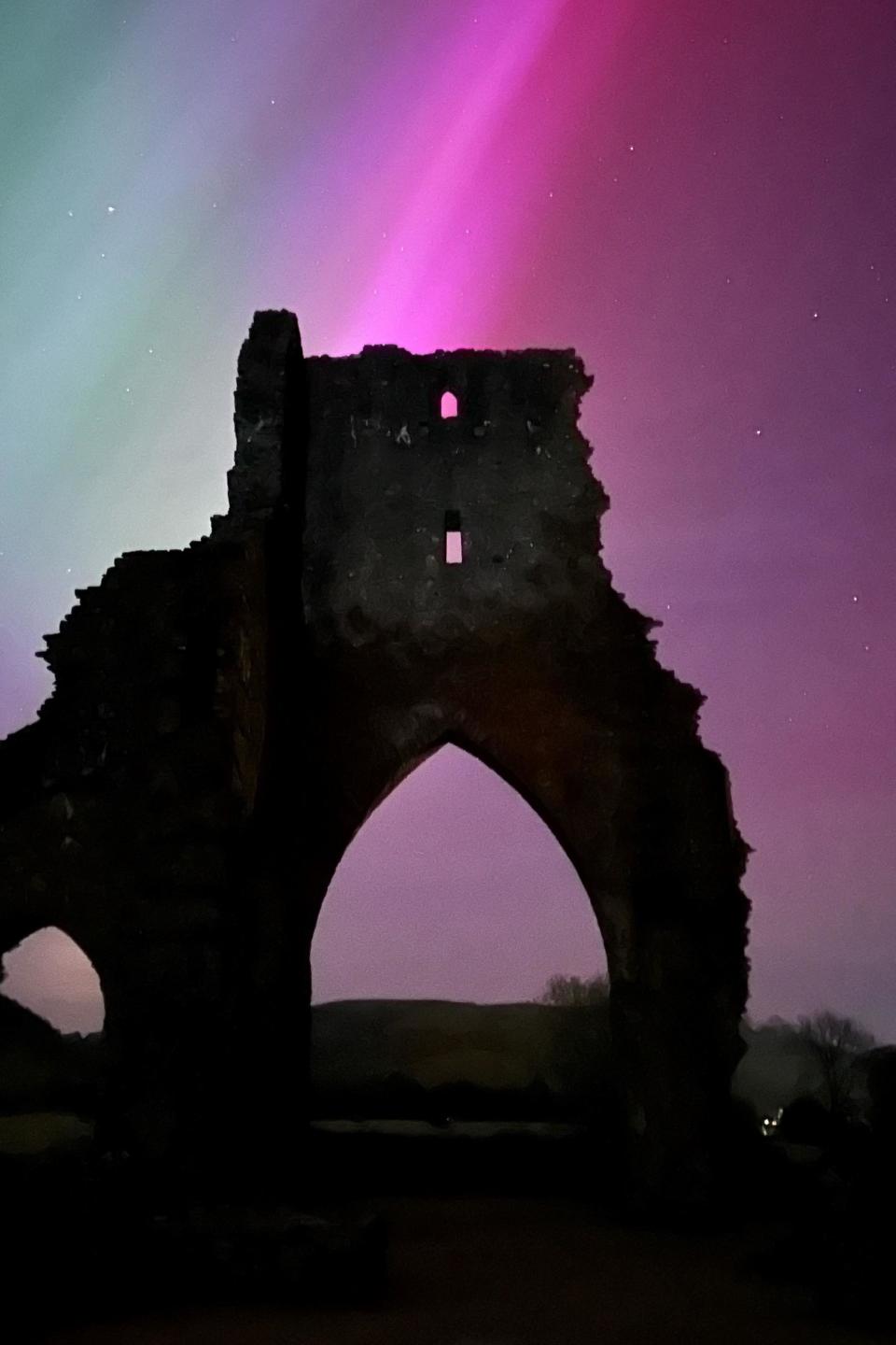 Castel ruins silhouetted against pinkish hues
