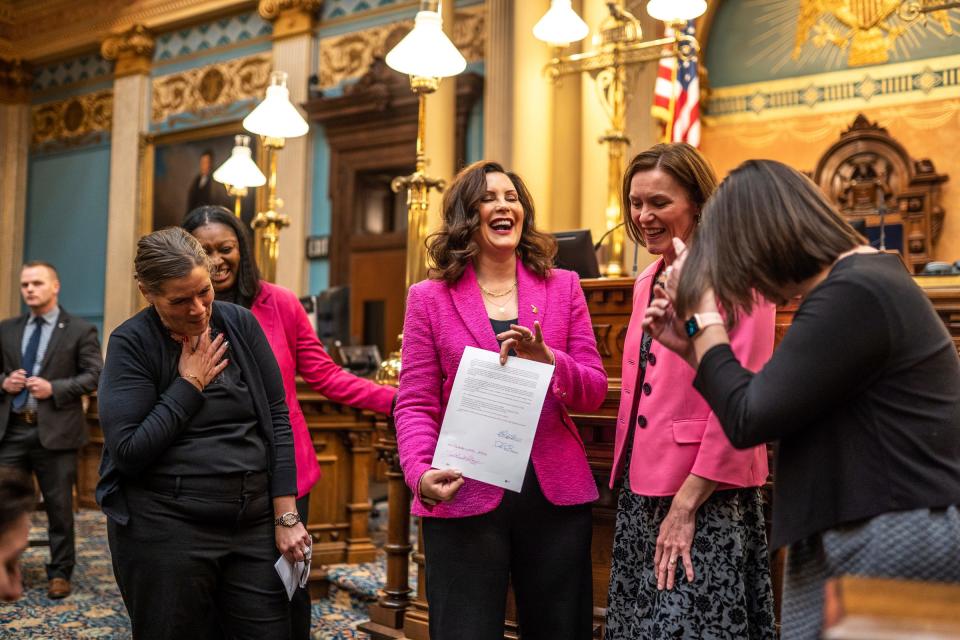 Gov. Gretchen Whitmer, center, shares a laugh with others while making sure the signature side is photographed after signing the final bill in the Reproductive Health Act on Monday, Dec. 11, 2023, at the Michigan State Capitol building in Lansing. The bill repeals Michigan's ban on insurance coverage for abortion without the purchase of a separate rider and implements other protections for doctors and patients.