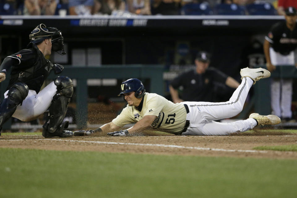 Vanderbilt's JJ Bleday (51) scores against Louisville catcher Henry Davis on a double by Ethan Paul during the ninth inning of an NCAA College World Series baseball game in Omaha, Neb., Friday, June 21, 2019. (AP Photo/Nati Harnik)