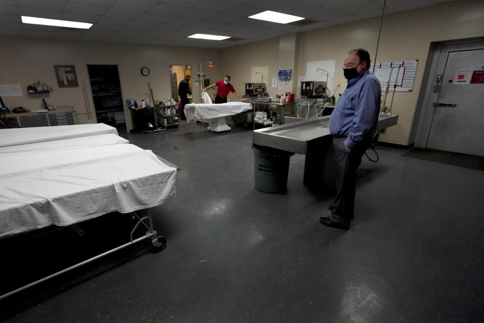 Owner Brian Simmons looks over the preparation room in mortuary as workers get ready to prepare a body Thursday, Jan. 28, 2021, in Springfield, Mo. Simmons has been making more trips to homes to pick up bodies to be cremated and embalmed since the pandemic hit. For many families, home is a better setting than the terrifying scenario of saying farewell to loved ones behind glass or during video calls amid the coronavirus pandemic. (AP Photo/Charlie Riedel)